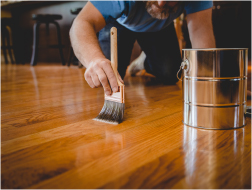 man varnishing a wood floor