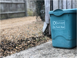 small green plastic recycling bin in an alley